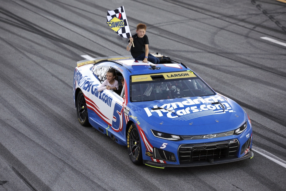 Kyle Larson drives to victory lane as his son, Owen Larson, waves the checkered flag after winning at Talladega on October 25, 2026.